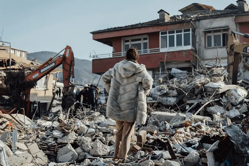 Persona osserva macerie dopo un terremoto.