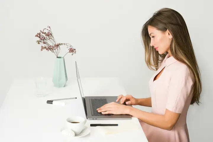 Donna al lavoro su laptop in ufficio moderno.