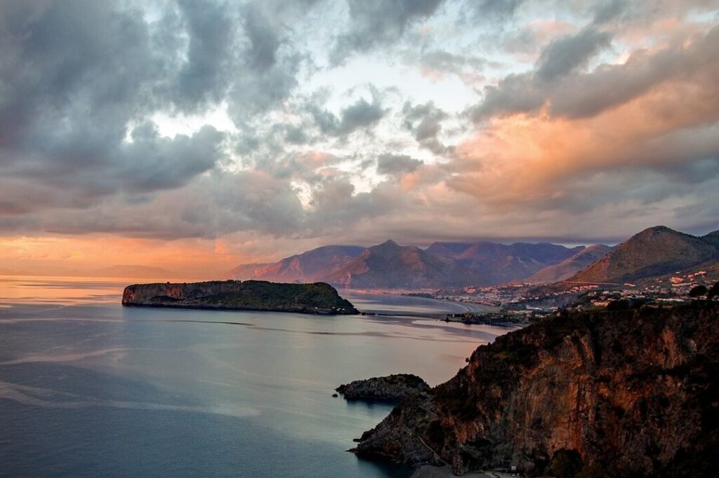Tramonto sul mare con costa e montagne