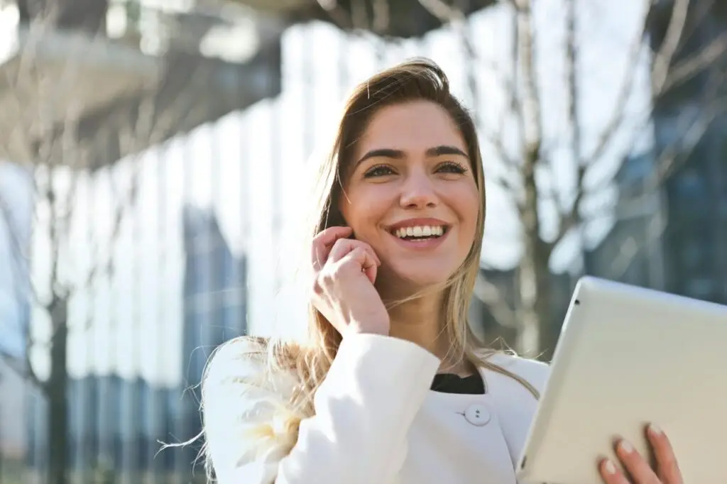 Donna sorridente con tablet parla al telefono.