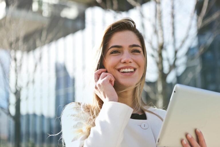 Donna sorridente con tablet parla al telefono.