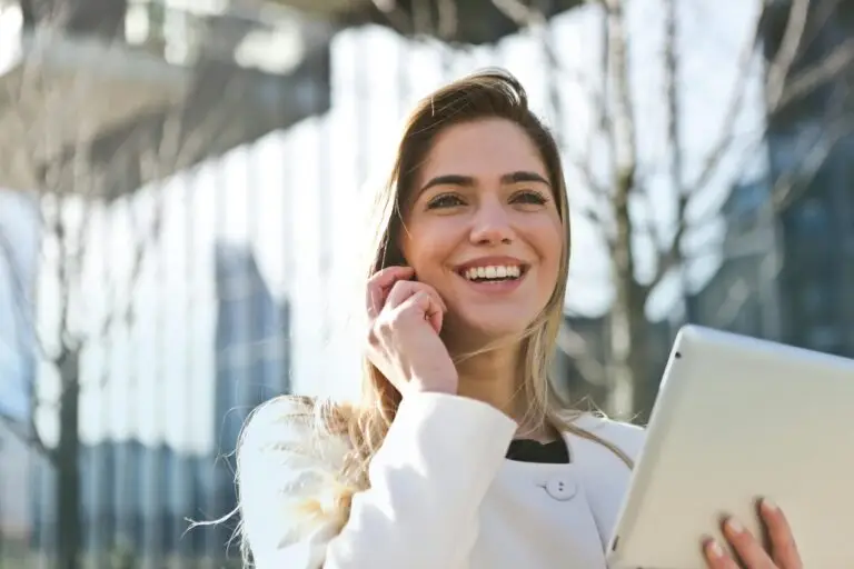 Donna sorridente con tablet parla al telefono.