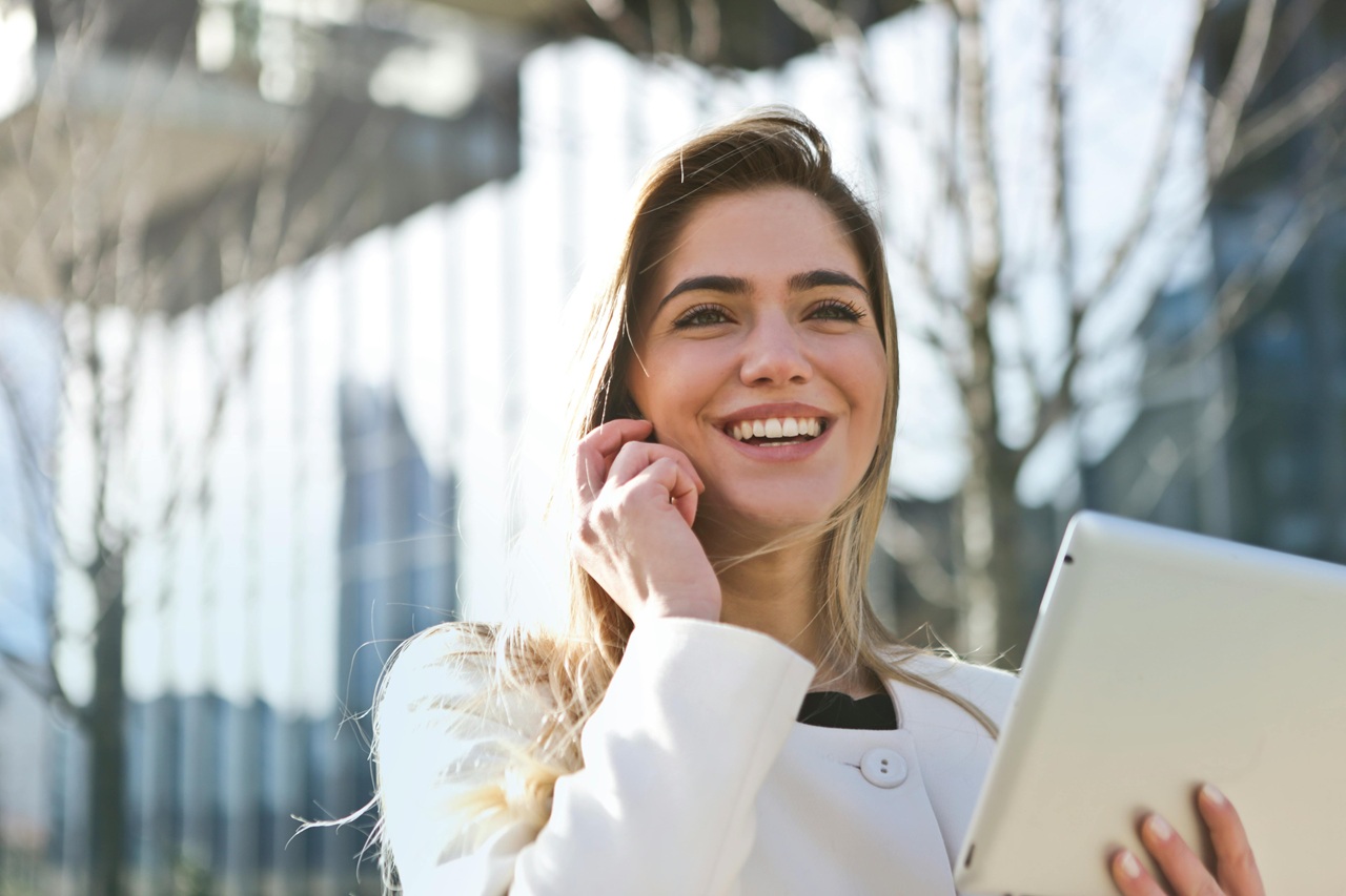 Donna sorridente con tablet parla al telefono.
