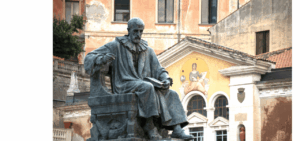 Statua storica in piazza, sfondo edificio antico.